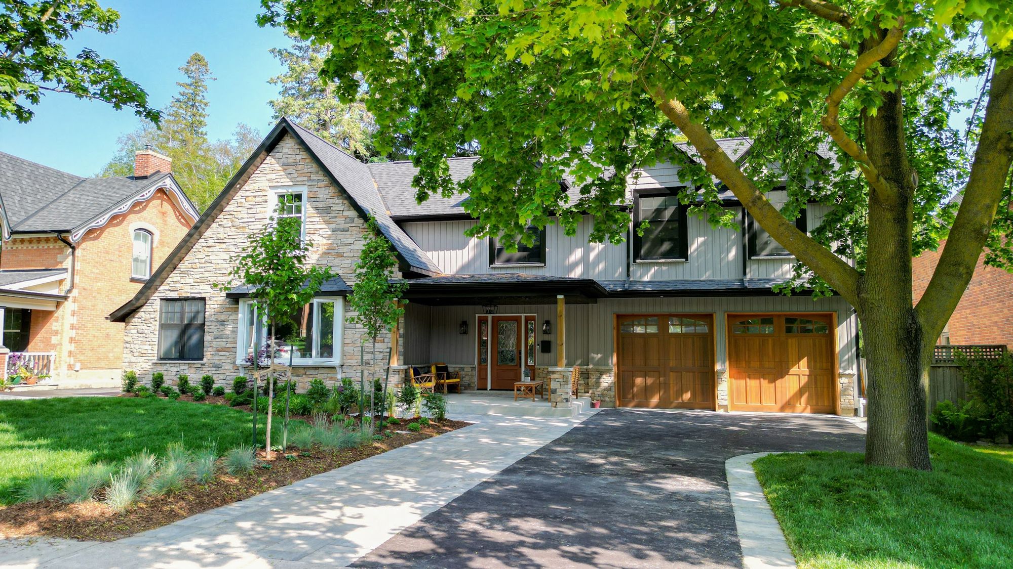 Home addition with stone front, board-and-batten siding and wood garage doors