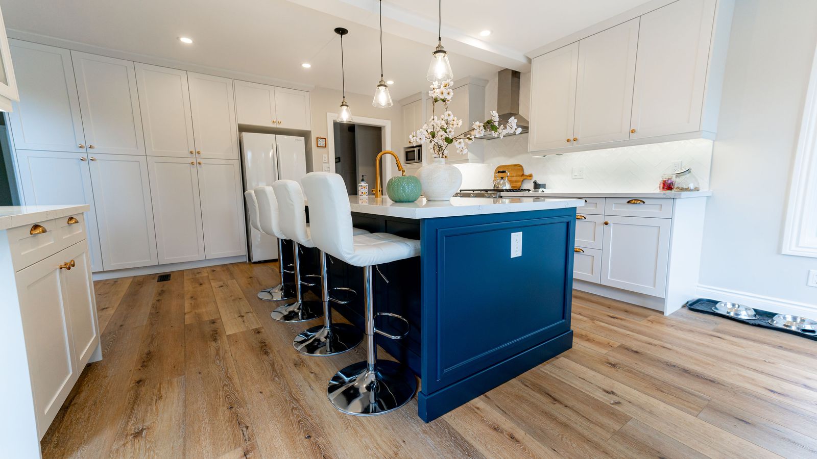 White shaker kitchen with navy island and pendant lights